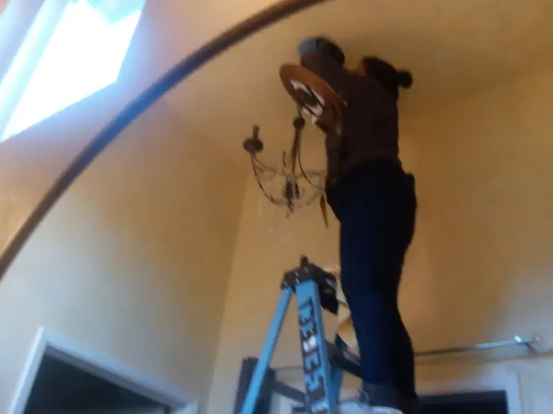 Electrician installing a chandelier in a Freeport residence